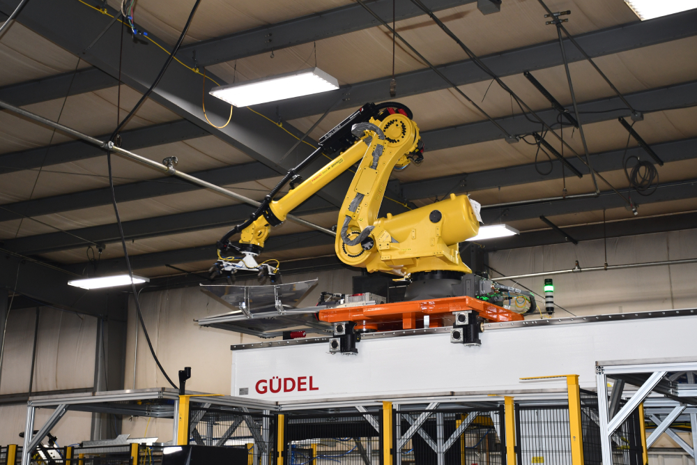 FANUC robot riding a Güdel robot transport unit in an automated axle shaft processing cell