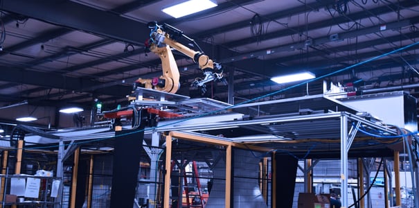 Robot with dual gripper tending stations from an elevated rail in the axle shaft cell