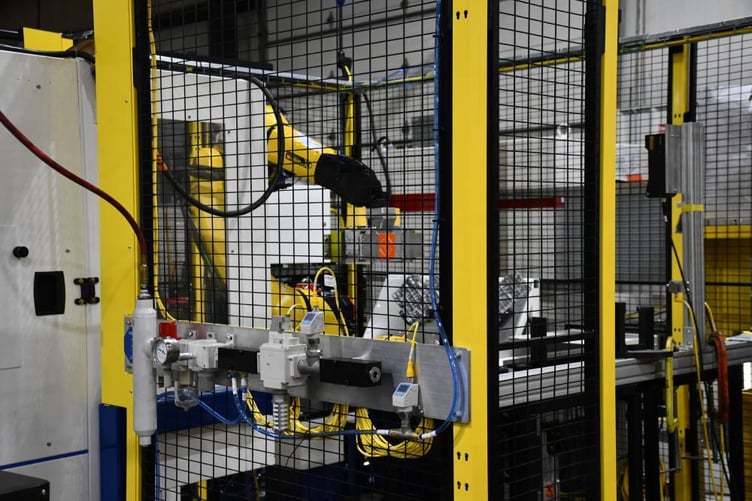 Robot tending the laser marking station inside a guarded cell with pneumatic controls in front