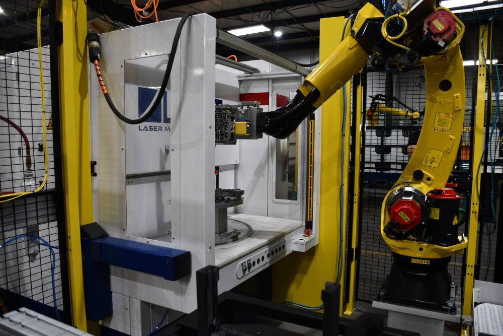 Robot loading an automotive valve body into a laser marking machine
